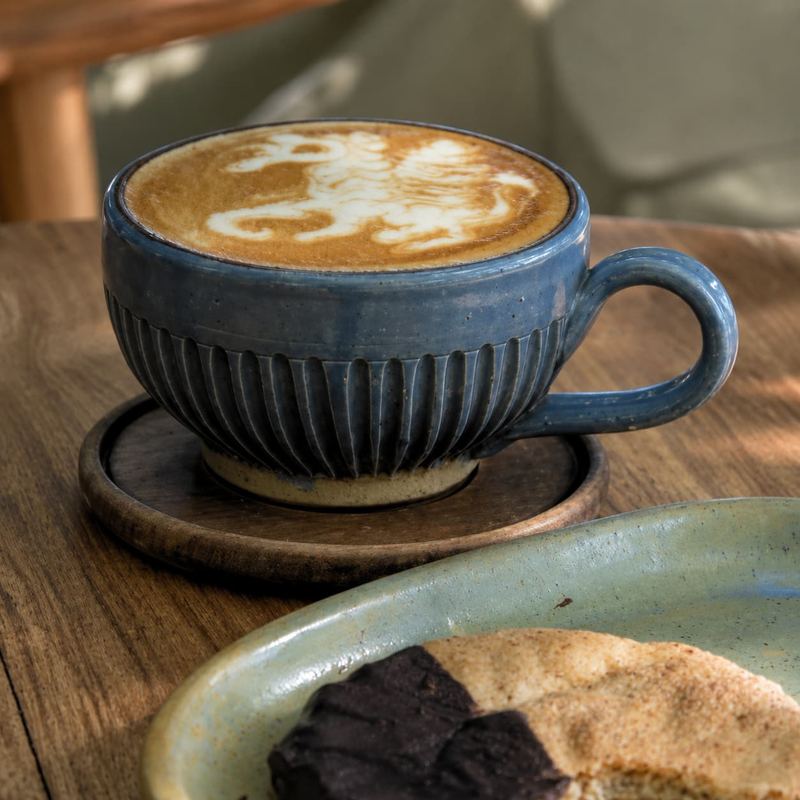 Coffee with latte art in a blue ribbed hand-thrown mug at Kāffi Colombo
