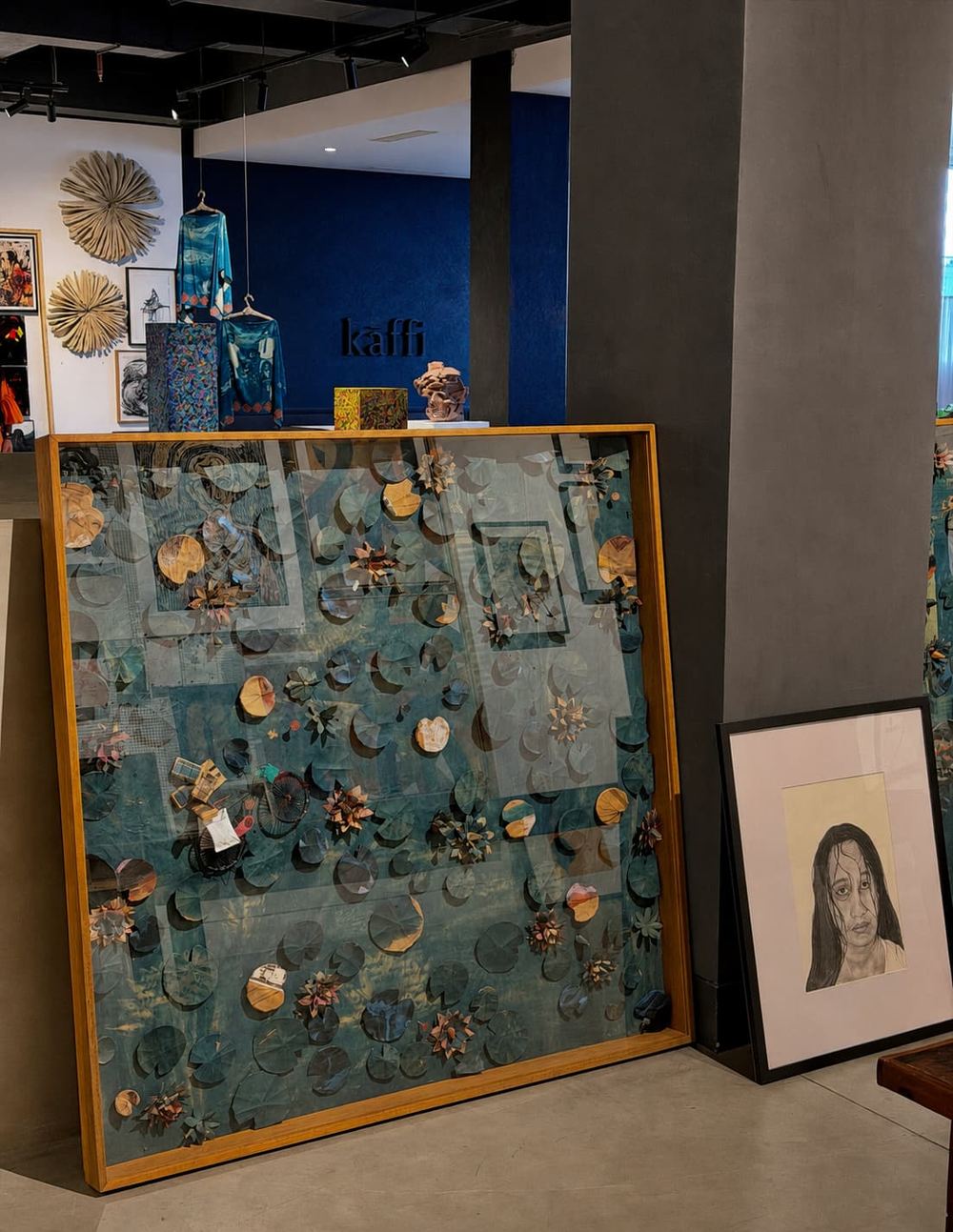 Framed artwork leaning against the blue Kāffi wall inside the Colombo gallery space
